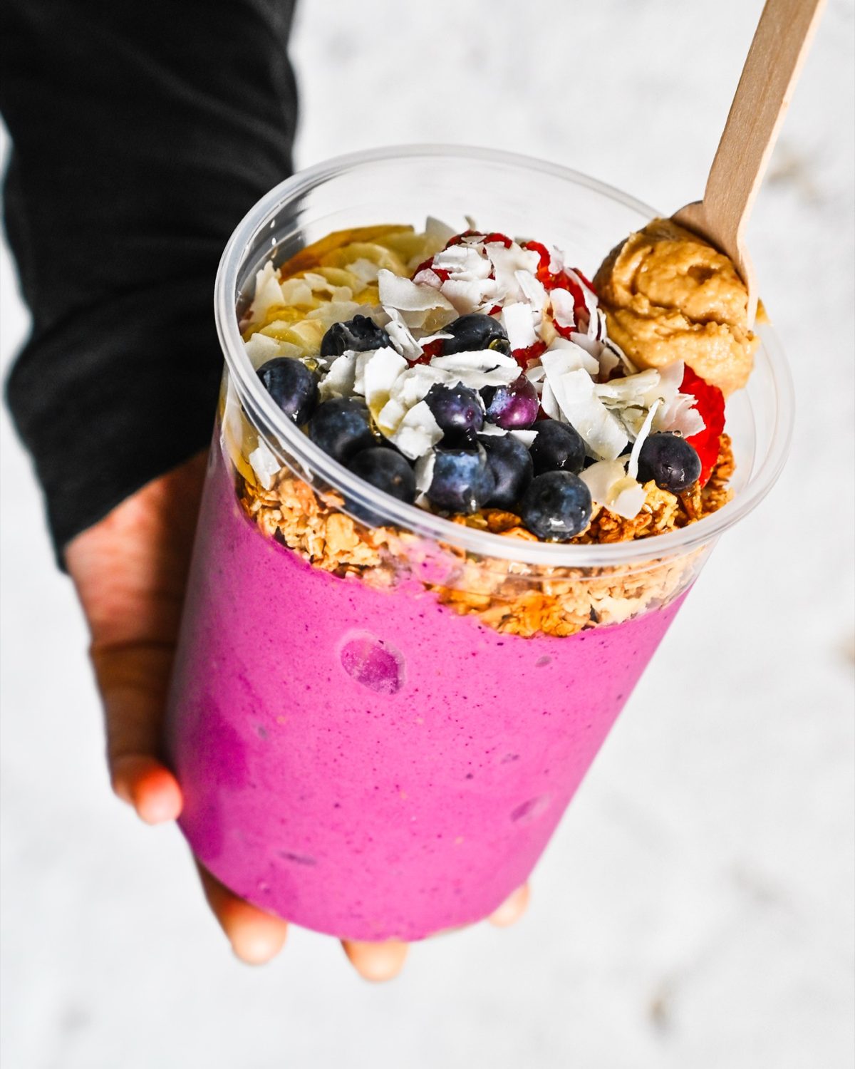 A protein bowl topped with fruit, granola, coconut and nut butter